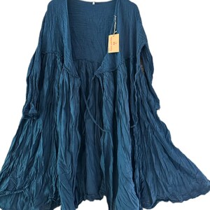 May include: A dark teal, long-sleeved, open-front duster cardigan made of a crinkled, textured fabric. The garment features a gathered waistline, a flowing silhouette, and a small rectangular tan tag attached to the upper chest area.