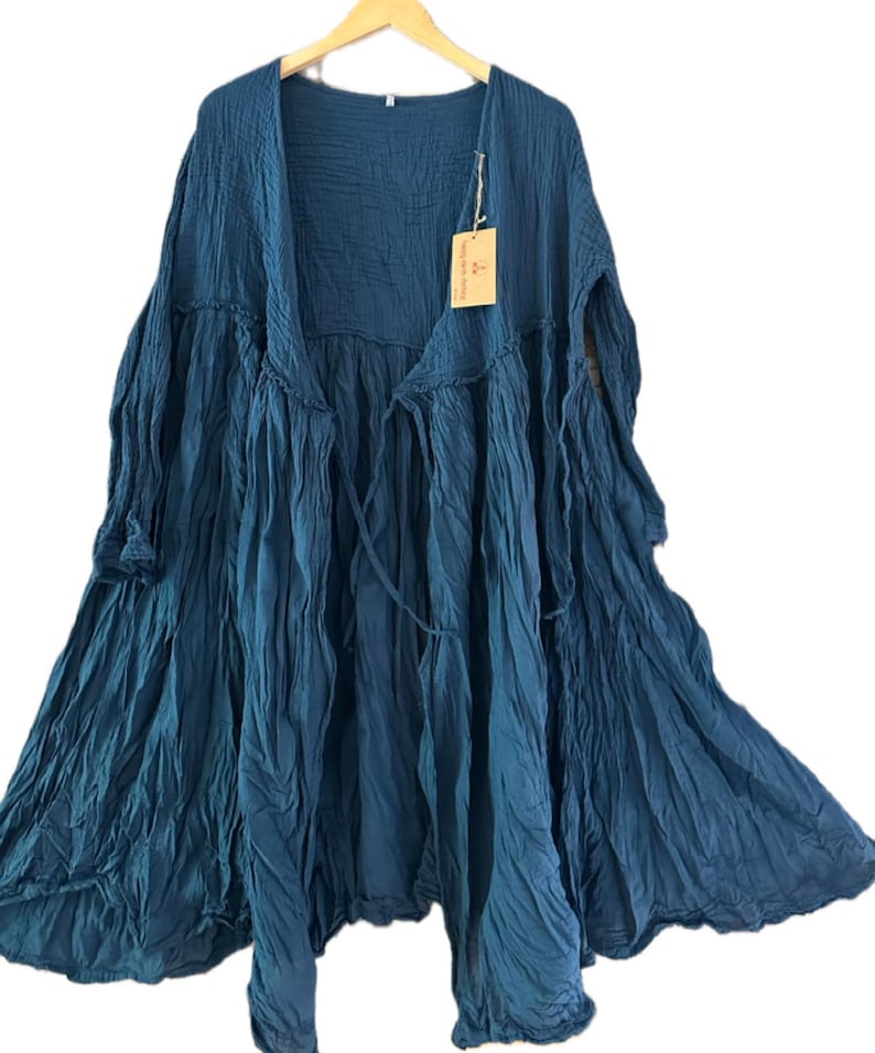 May include: A dark teal, long-sleeved, open-front duster cardigan made of a crinkled, textured fabric. The garment features a gathered waistline, a flowing silhouette, and a small rectangular tan tag attached to the upper chest area.