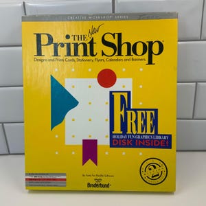 May include: A yellow box for "The New Print Shop" software. The box features the text "The Print Shop" in large, bold letters, with the tagline "Designs and Prints Cards, Stationery, Flyers, Calendars and Banners." It also says "FREE Holiday Fun Graphics Library Disk Inside!"