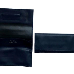Puede incluir: Una bolsa de tabaco para liar de cuero negro con el texto "U Like the Relax Zone" impreso en la parte delantera.