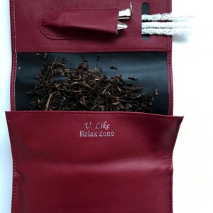 Puede incluir: Una bolsa de tabaco de cuero rojo con forro negro. La bolsa tiene un bolsillo para una herramienta y una ranura para un limpiador de pipa. La bolsa est&aacute; abierta y hay tabaco dentro. La bolsa tiene el texto "U. Like Relax Zone" impreso en la parte delantera.