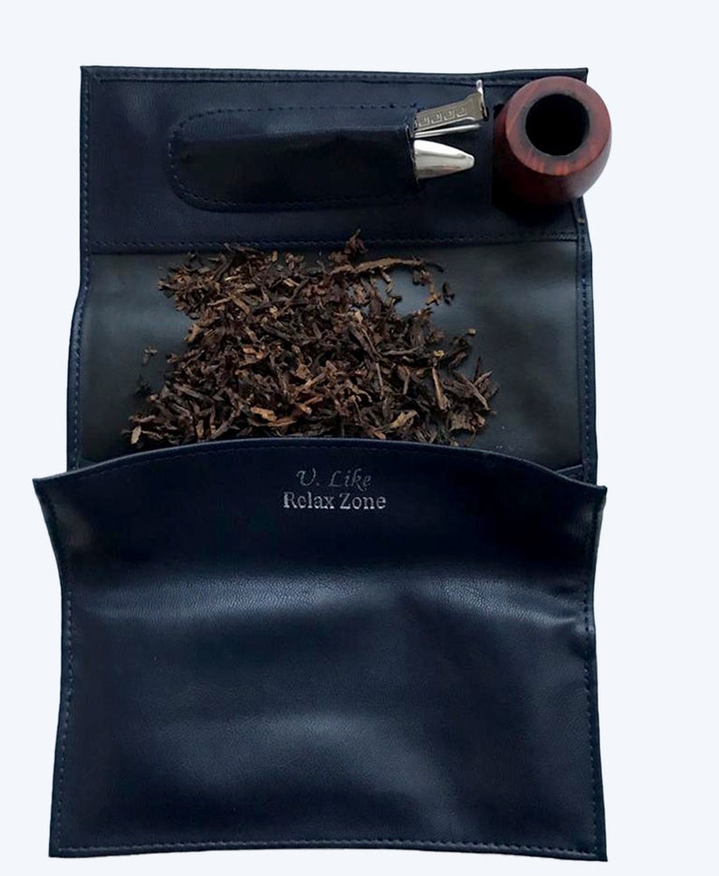 Puede incluir: Una bolsa de tabaco de cuero azul con una pipa, un tamp&oacute;n y tabaco en su interior. La bolsa tiene el texto "V. Like Relax Zone" impreso en la parte delantera.