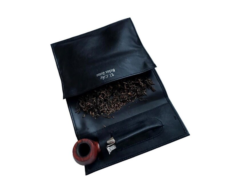 Puede incluir: Bolsa de tabaco de cuero negro con una pipa y tabaco en su interior. La bolsa tiene el texto "D'Life Relax Zone" impreso en ella.
