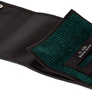 May include: A black leather cigarette case with a green corduroy lining. The case has a flap that closes with two silver snaps. The lining has a small pocket with the text "U Like Relax Zone" printed in white.