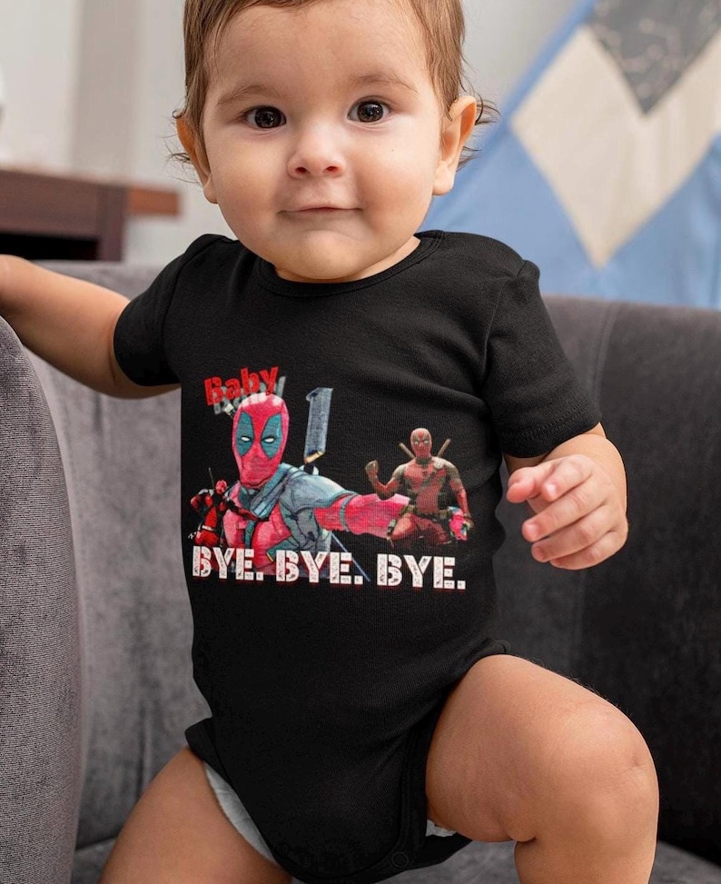 Puede incluir: Un body de beb&eacute; negro con un gr&aacute;fico de Deadpool rojo y negro y el texto "Baby Deadpool" y "BYE. BYE. BYE."