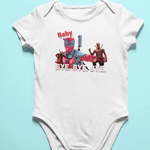 Puede incluir: Un body blanco para beb&eacute; con un gr&aacute;fico de Deadpool rojo y negro. El texto "Baby" y "Bye Bye Bye" est&aacute; impreso en el body.