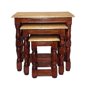 May include: A set of three nested tables with dark brown wooden frames and turned legs. Each table features a rectangular top with a textured, light gold-colored surface and a decorative rope-patterned border along the edges of the tabletop.