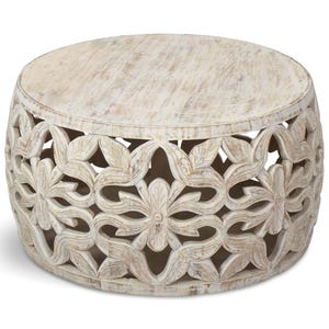 May include: Round, whitewashed wooden coffee table. The table has a carved floral design around the sides and a flat top. The table is approximately 46 cm in height and 91 cm in diameter.