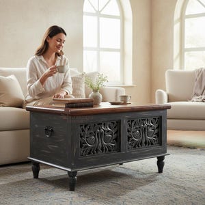 Könnte beinhalten: Ein rechteckiger Couchtisch mit dunkelgrauem, abgenutztem Finish und zwei Frontpaneelen mit detaillierten, handgeschnitzten Pfauenmotiven. Der Tisch hat eine glatte braune Holzplatte, vier gedrechselte Beine und seitliche Griffe aus schwarzem Metall.