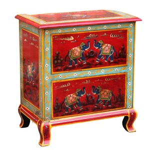 Può includere: Un baule in legno rosso con due cassetti, dipinto con elefanti colorati e motivi floreali. Il baule ha dettagli dorati e poggia su quattro gambe intagliate.