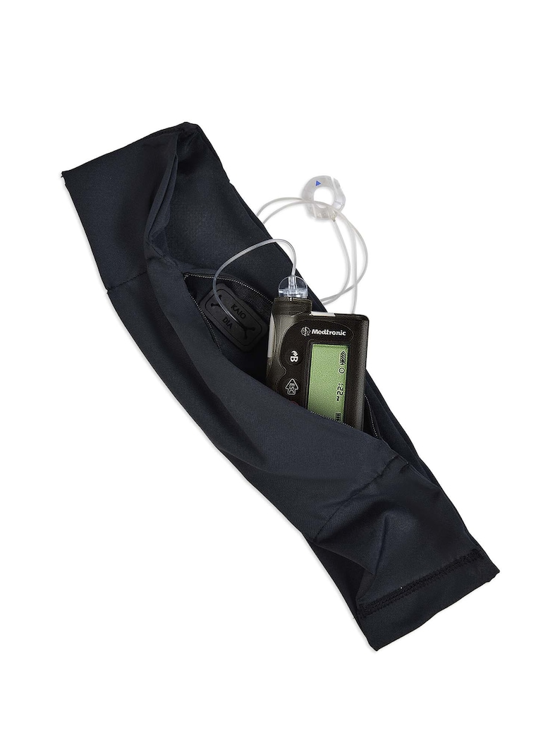 May include: A black sleeve designed to hold a Medtronic insulin pump and related medical devices. The pump is visible with a screen displaying information. The sleeve has a small pocket with the text "KAIO DIA".