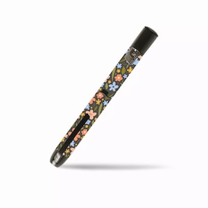 Peut inclure: Un dispositif médical noir avec un motif floral de fleurs orange, bleues et jaunes sur un fond sombre. L'appareil a un capuchon noir et un bouton argenté. L'appareil est incliné sur un fond blanc.