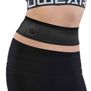 Könnte beinhalten: Schwarzer Trainingsgürtel mit einem kleinen schwarzen Knopf auf der Vorderseite. Der Gürtel wird über einer schwarzen Leggings und einem schwarzen Sport-BH mit dem in Weiß gedruckten Wort "UWEAR" getragen.