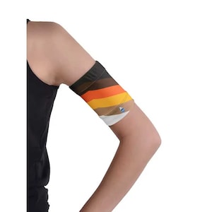 May include: A black and multi-colored arm sleeve with horizontal stripes in shades of brown, orange, yellow, and white. The sleeve is worn on the arm and has a small blue emblem. The sleeve is made of a stretchy material.