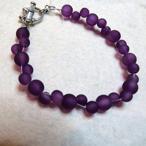 May include: A purple glass bead bracelet with a silver clasp.