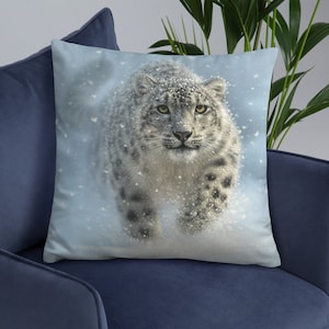 May include: A snow leopard walks through a snowy landscape. The leopard is white with black spots and has a light blue background.
