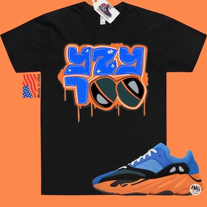 May include: Black t-shirt with a blue and orange graphic that says "YZY 700" with sunglasses.  A pair of blue and orange sneakers with a black sole.