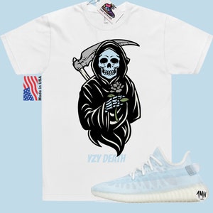 May include: White t-shirt featuring a black and white illustration of the Grim Reaper holding a flower. The text "YZY DEATH" is printed below the illustration. A pair of light blue Yeezy trainers are shown below the t-shirt.
