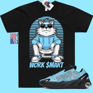 May include: Black t-shirt featuring a cartoon cat wearing sunglasses and a blue hoodie. The cat is sitting with the text "WORK $MART" underneath. A pair of blue and black trainers are shown below the t-shirt.