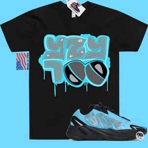 May include: Black t-shirt with a blue and gray graphic that says "Yeezy Too" with dripping paint. A pair of black and blue sneakers with a white logo.