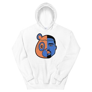 May include: White hoodie with a graphic of a cartoon bear and a person's face, split down the middle. The bear is orange and the person's face is blue. The text "YZY" is on the person's forehead.