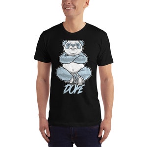 May include: Black t-shirt featuring a blue and white panda bear illustration wearing a hat and sitting with its arms crossed. The text "DOPE" is printed below the panda.