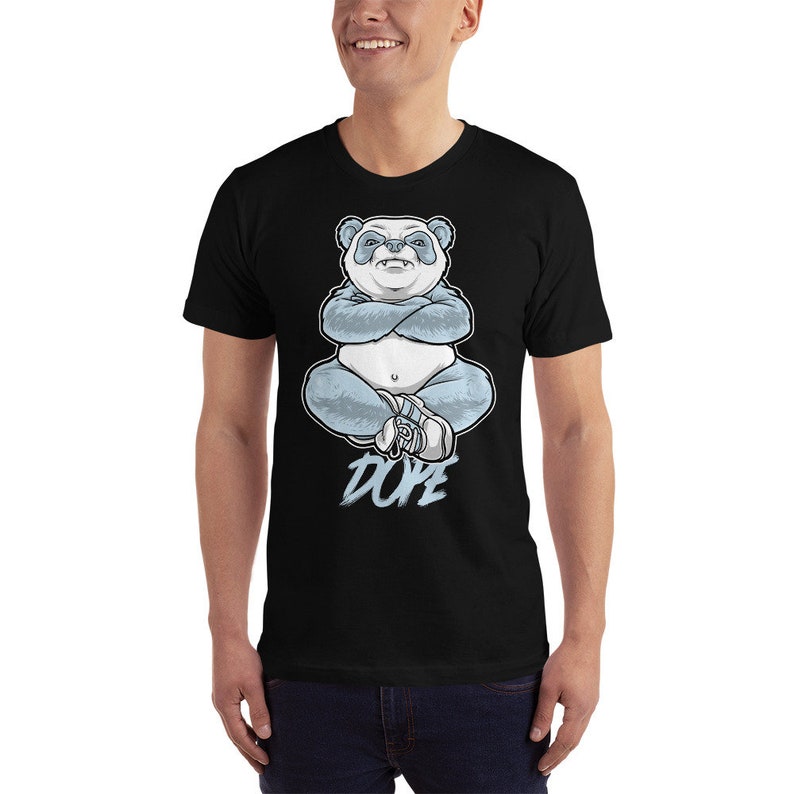 May include: Black t-shirt featuring a blue and white panda bear illustration wearing a hat and sitting with its arms crossed. The text "DOPE" is printed below the panda.