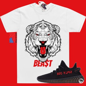 May include: White t-shirt with a black and white lion graphic and the word "BEAST" in red. A black and red Adidas Yeezy Boost 350 V2 sneaker is shown below the shirt.