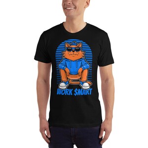 Op de afbeelding: Zwart T-shirt met een cartoonkat die een zonnebril en een blauwe hoodie draagt. De kat zit met gekruiste benen en de tekst "WORK $MART" staat onder de kat.