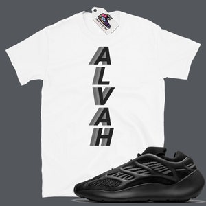 Puede incluir: Camiseta blanca con la palabra "ALVAH" impresa verticalmente en letras negras y grises. Un par de zapatillas negras con suela blanca.