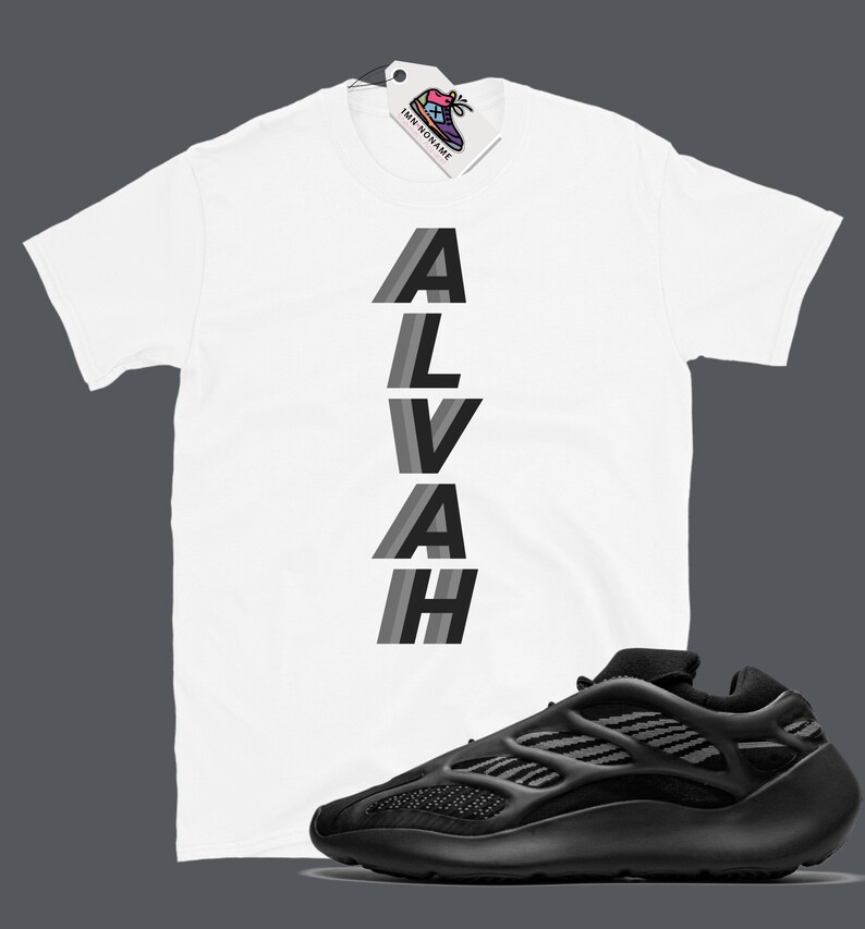 Puede incluir: Camiseta blanca con la palabra "ALVAH" impresa verticalmente en letras negras y grises. Un par de zapatillas negras con suela blanca.