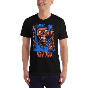 May include: Black t-shirt with a graphic of a red skull wearing a blue hoodie and making a hand gesture. The text "424 700" is printed below the graphic.