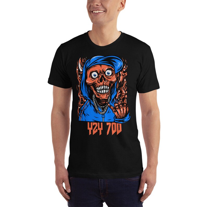 May include: Black t-shirt with a graphic of a red skull wearing a blue hoodie and making a hand gesture. The text "424 700" is printed below the graphic.
