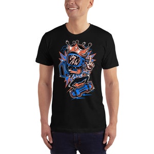 Pu&ograve; includere: Una maglietta nera con un'illustrazione di un personaggio dei cartoni animati che indossa un casco blu e una corona, mentre fa skateboard. Il personaggio indossa una camicia a motivi blu e arancioni e ha uno skateboard blu e arancione.