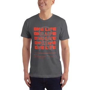 Puede incluir: Una camiseta gris oscuro con un gr&aacute;fico de calavera y huesos cruzados rojos y el texto "ONE LIFE" repetido cuatro veces. El texto est&aacute; en una fuente de estilo graffiti. La parte inferior de la camiseta tiene el texto "YOU HAVE ONE CHANCE" en una fuente m&aacute;s peque&ntilde;a.