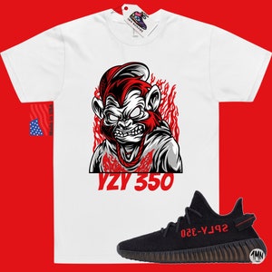 May include: White t-shirt with a red and black illustration of a monkey wearing a hat and a chain. The text "YZY 350" is printed below the monkey. Black and red sneakers with the text "YZY 350" on the side.