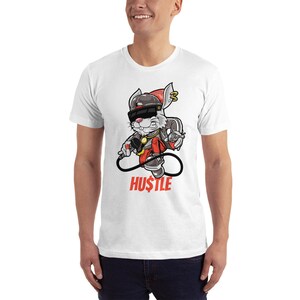May include: White t-shirt with a cartoon rabbit wearing sunglasses, a hat, and a gold chain. The rabbit is holding a microphone and the text "HU$TLE" is printed below the rabbit.
