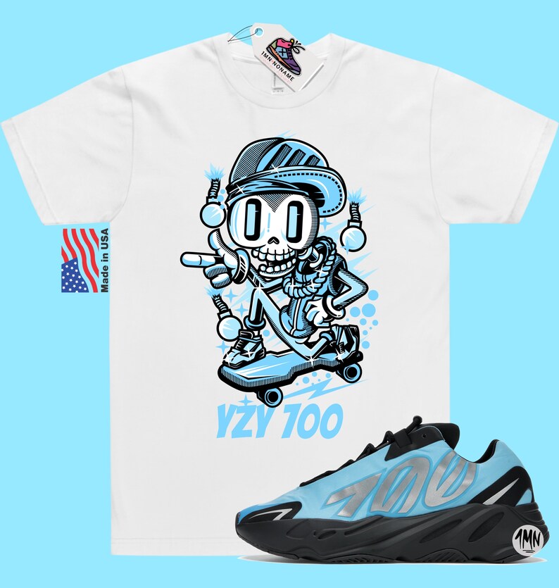 May include: A white t-shirt with a cartoon skeleton wearing a blue hat and jacket, skateboarding. The text "YZY 700" is printed below the image. A pair of blue and black Yeezy 700 sneakers are also pictured.