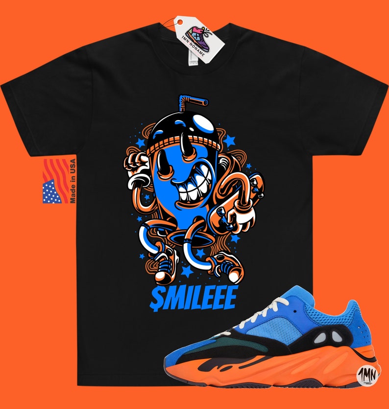May include: Black t-shirt featuring a cartoon illustration of a blue and orange drink with a straw and the text "$MILEEE". A pair of blue and orange trainers with a black sole.