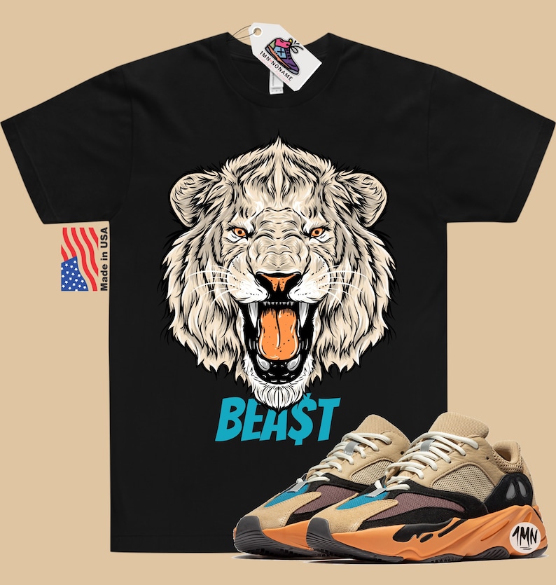 May include: Black t-shirt featuring a detailed illustration of a roaring white lion's head with the word "BEAST" in blue. Paired with tan, brown, and orange sneakers. Includes a "Made in USA" tag and a shoe tag.