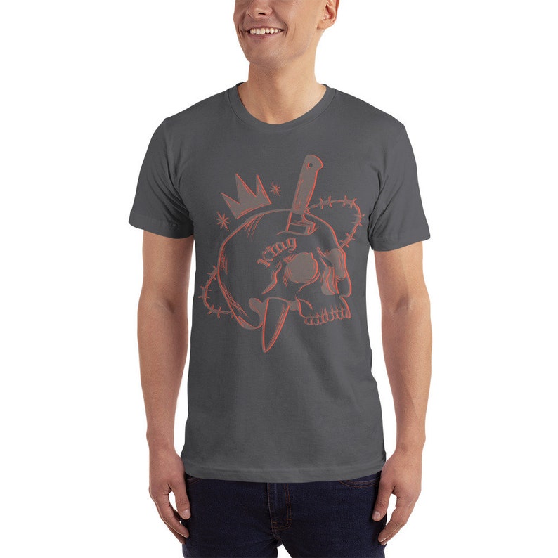 May include: A dark gray t-shirt with a red outline of a skull with a knife through it. The skull has a crown on top and the word "king" tattooed on it. The skull is surrounded by barbed wire.
