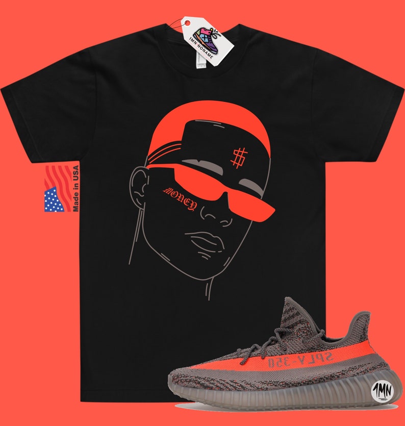 May include: Black t-shirt with a red outline of a person wearing sunglasses and a hat with a dollar sign on it. The text "Money" is on the person's cheek. A pair of grey and orange Yeezy sneakers are in the bottom right corner of the image.
