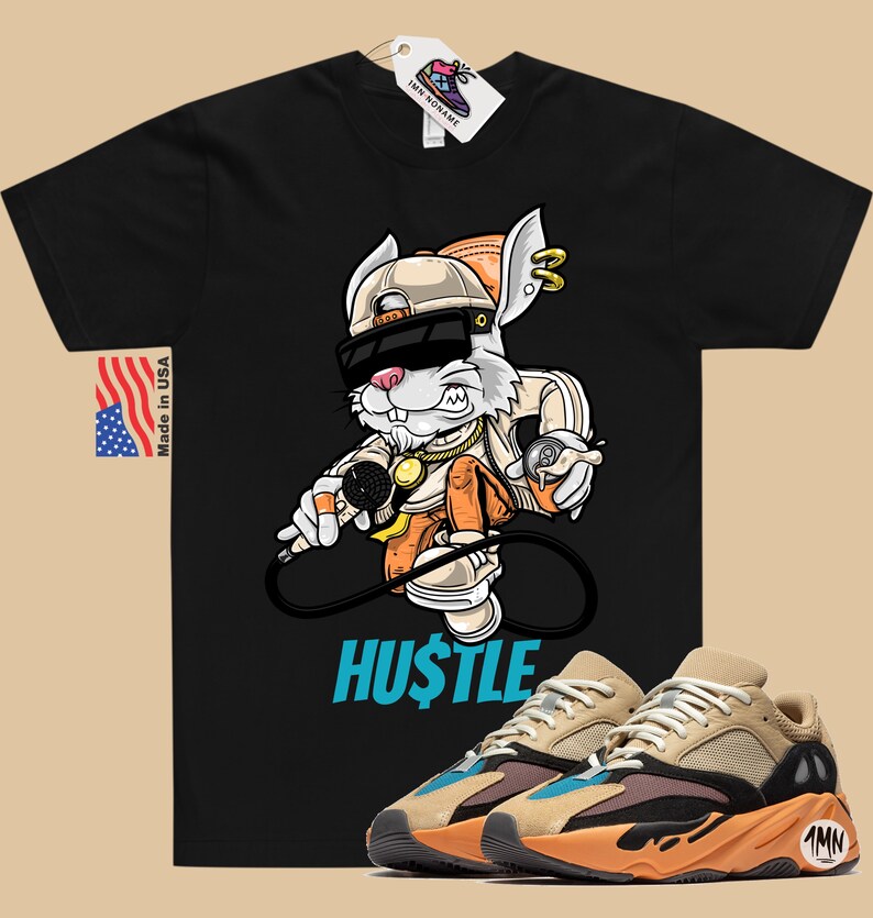 May include: Black t-shirt with a cartoon rabbit wearing sunglasses and a hat, holding a microphone and a spray can. The text "HUSTLE" is printed below the rabbit. A pair of tan, orange, and blue sneakers are shown below the t-shirt.