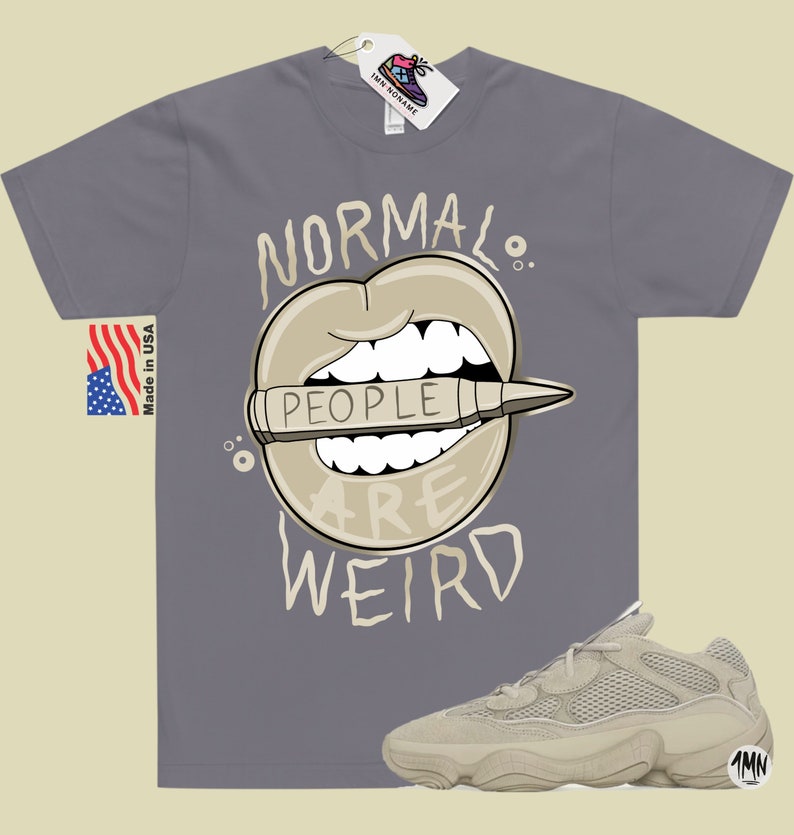 Pode incluir: Uma camiseta cinza com o texto "Normal People Are Weird" em preto e branco. O texto &eacute; cercado por uma imagem de desenho animado de uma boca com um l&aacute;pis dentro. O l&aacute;pis tem a palavra "People" escrita nele. Tamb&eacute;m &eacute; mostrado um par de t&ecirc;nis bege.