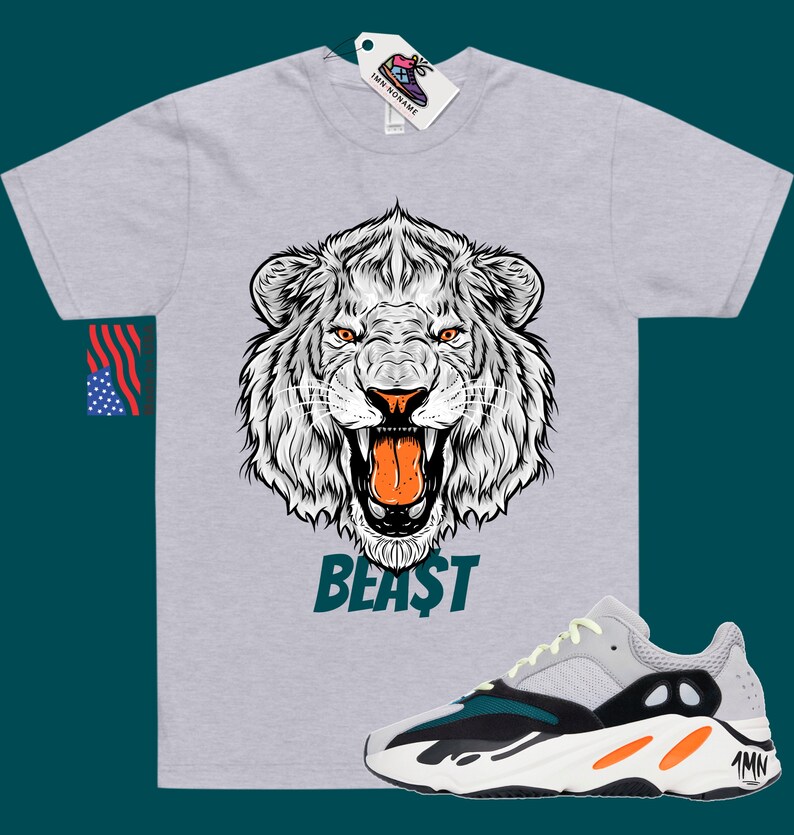 May include: A grey t-shirt with a white lion graphic and the word "BEAST" printed on the front. A pair of light grey, black, and orange trainers with the word "Yeezy" on the side.