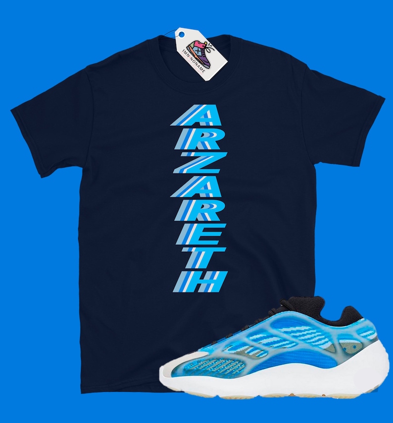 Pu&ograve; includere: Una t-shirt blu navy con la parola "ARZARETH" stampata verticalmente in strisce blu e bianche. Un paio di scarpe da ginnastica blu e bianche con suola bianca.