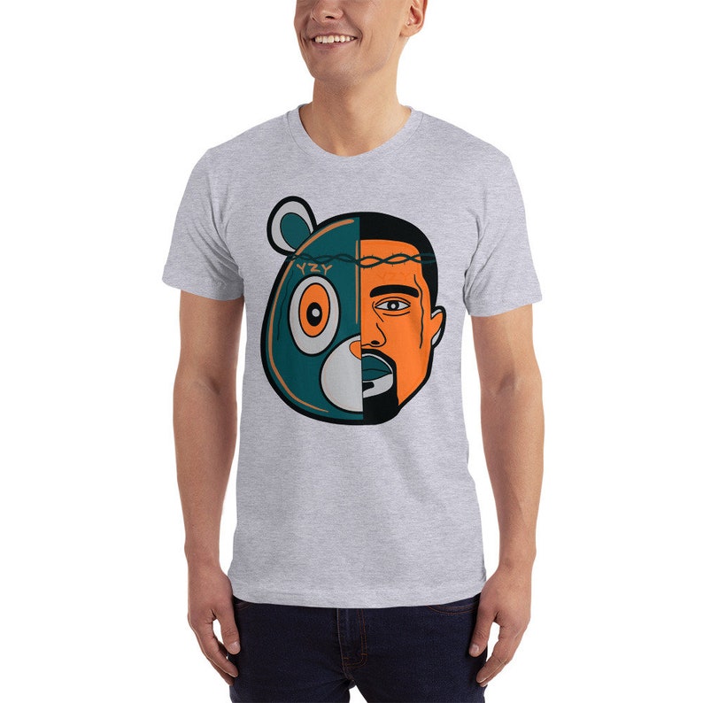 May include: A grey t-shirt with a graphic of a cartoon bear head with the word "YZY" on the forehead and a human face on the right side of the head.