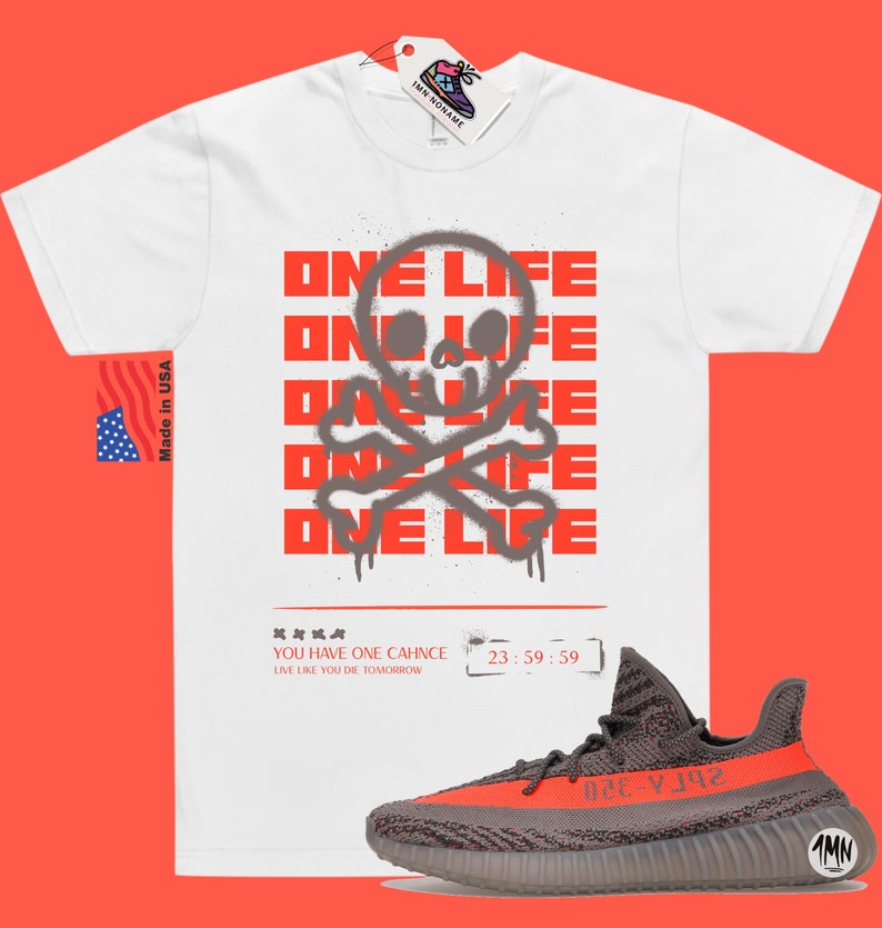Puede incluir: Camiseta blanca con un gr&aacute;fico rojo de calavera y huesos cruzados y el texto "ONE LIFE" repetido varias veces. El texto est&aacute; en estilo de pintura en aerosol. Debajo del gr&aacute;fico est&aacute; el texto "YOU HAVE ONE CHANCE LIVE LIKE YOU DIE TOMORROW" y los n&uacute;meros "23:59:59". Un par de zapatillas grises y rojas se muestra debajo de la camiseta.