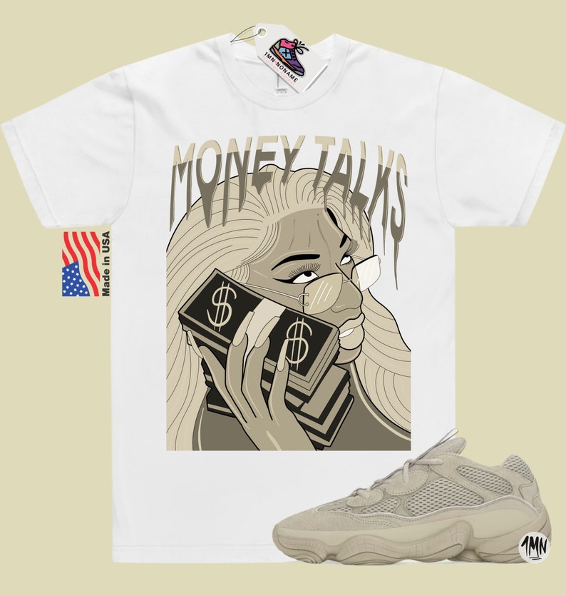 May include: White t-shirt with a graphic of a woman with blonde hair wearing glasses and holding a stack of money to her ear. The text "MONEY TALKS" is above the woman. A pair of beige sneakers are in the bottom right corner of the image.