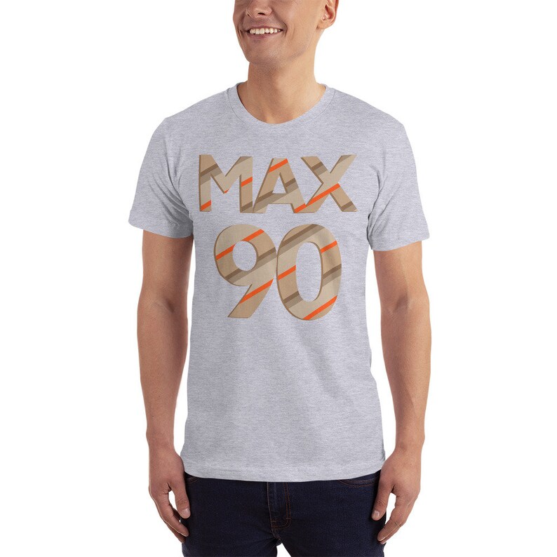 May include: A grey t-shirt with the text "MAX 90" printed on the front. The text is in a brown and orange striped font.